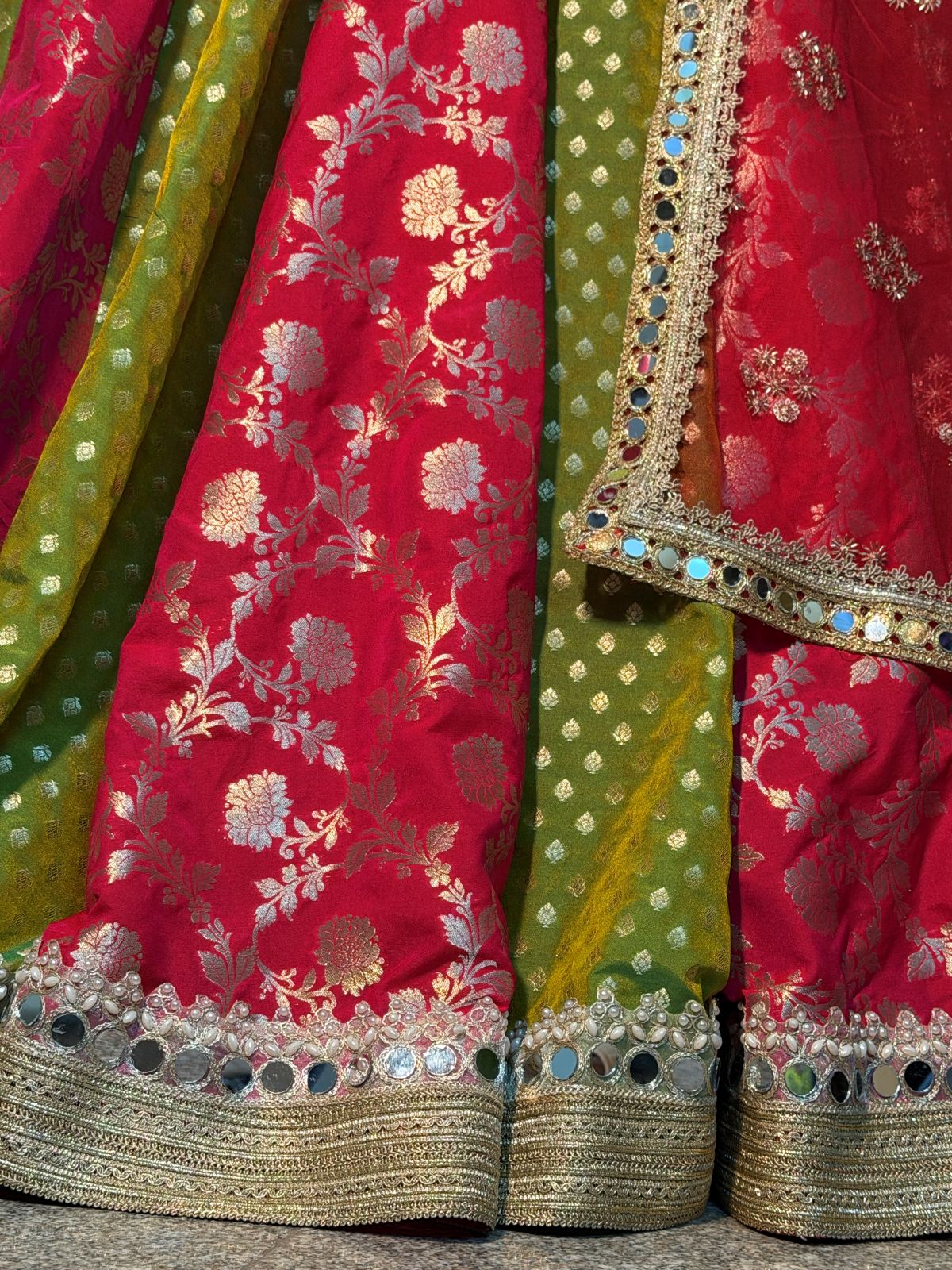 Back view of flared pink and green lehenga with gold-toned hem
