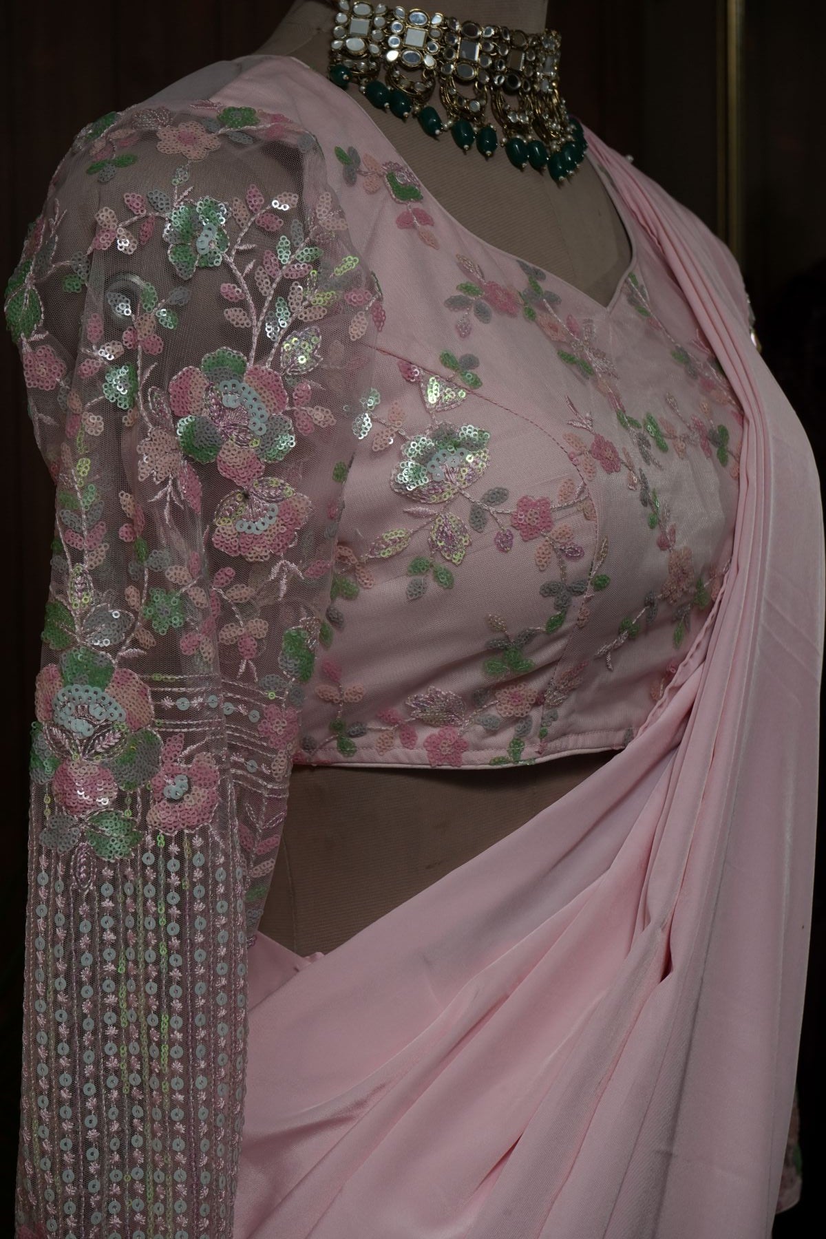 Back view of blush pink ruffle saree and blouse with sheer upper-back panel