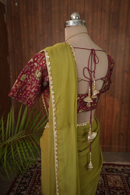 Front view of olive green georgette saree with gold-toned border and maroon motif blouse