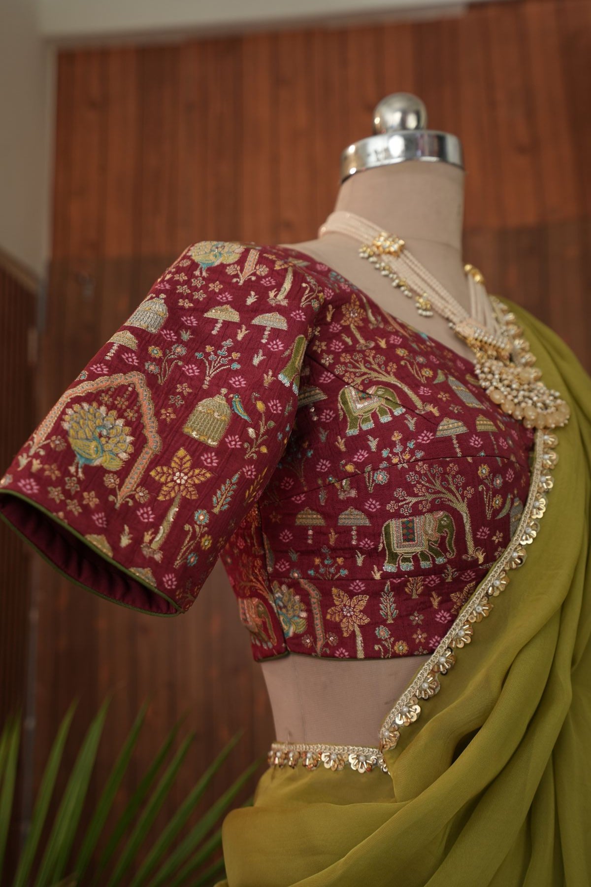 Close-up of gold-toned decorative tassels on maroon blouse tie strings