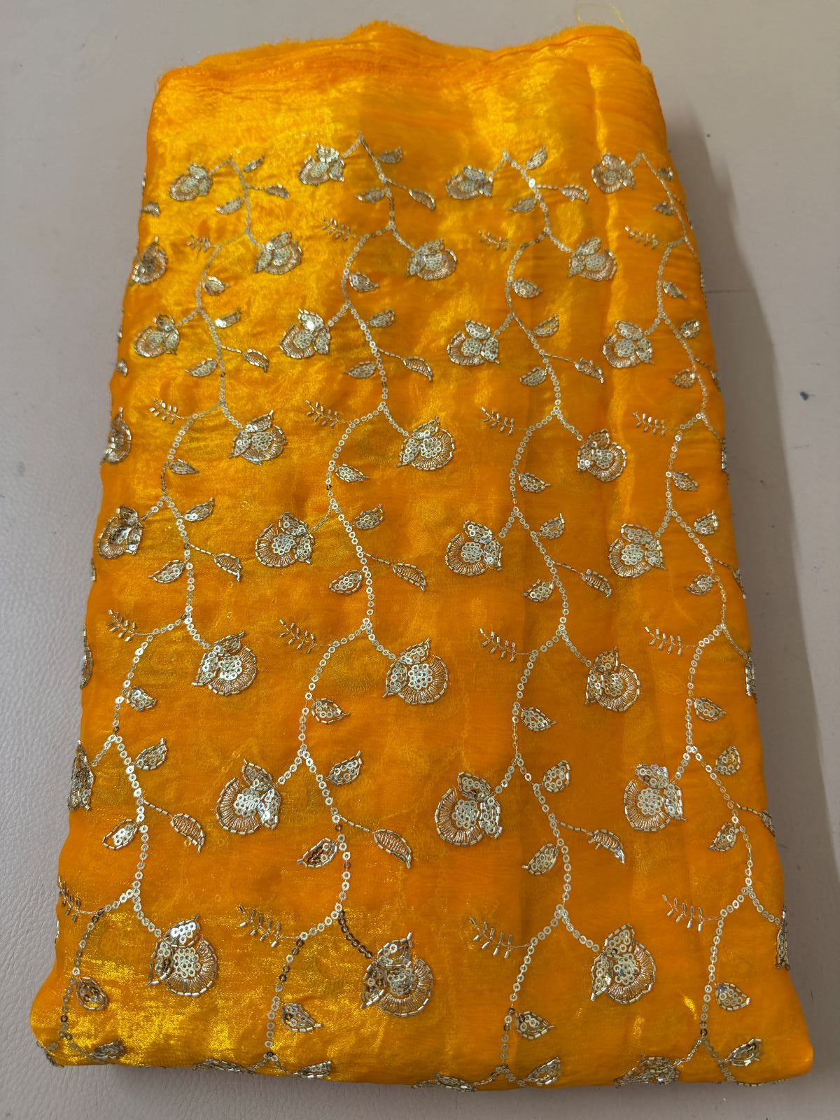 Full view of mustard-gold lehenga skirt with all-over floral metallic embellishment and ornate hem border