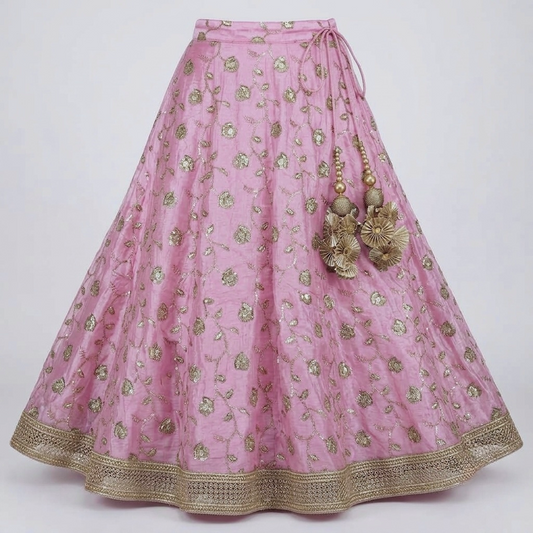 Full view of blush pink embellished lehenga with gold border and statement tassel detail