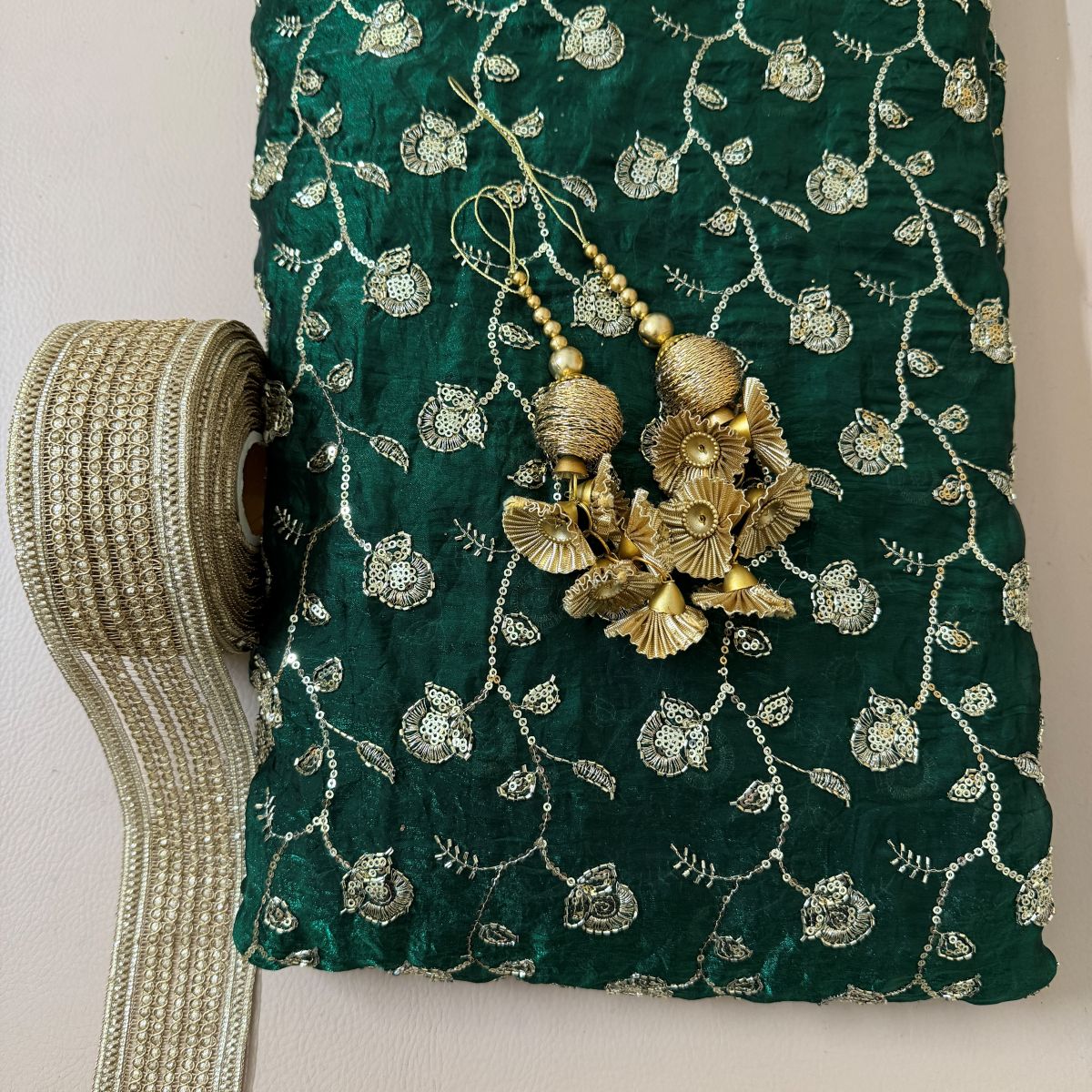 Close-up of teal green lehenga skirt embroidery, decorative latkan and embellished border