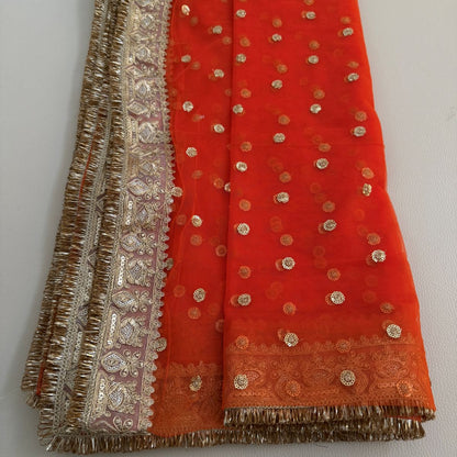 Close-up of orange dupatta with ornate floral border and fringe edging
