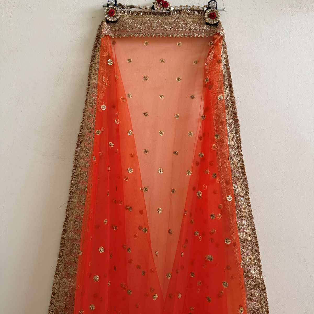 Full view of orange embellished dupatta with gold border and fringe