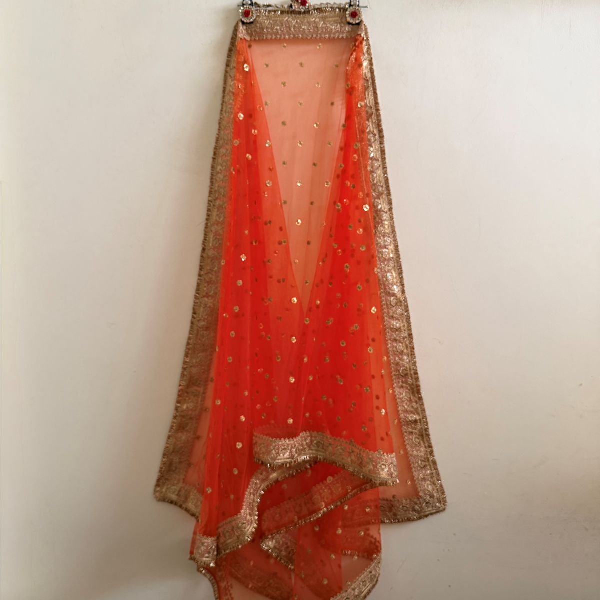 Orange embellished dupatta spread out with ornate border and fringe edging