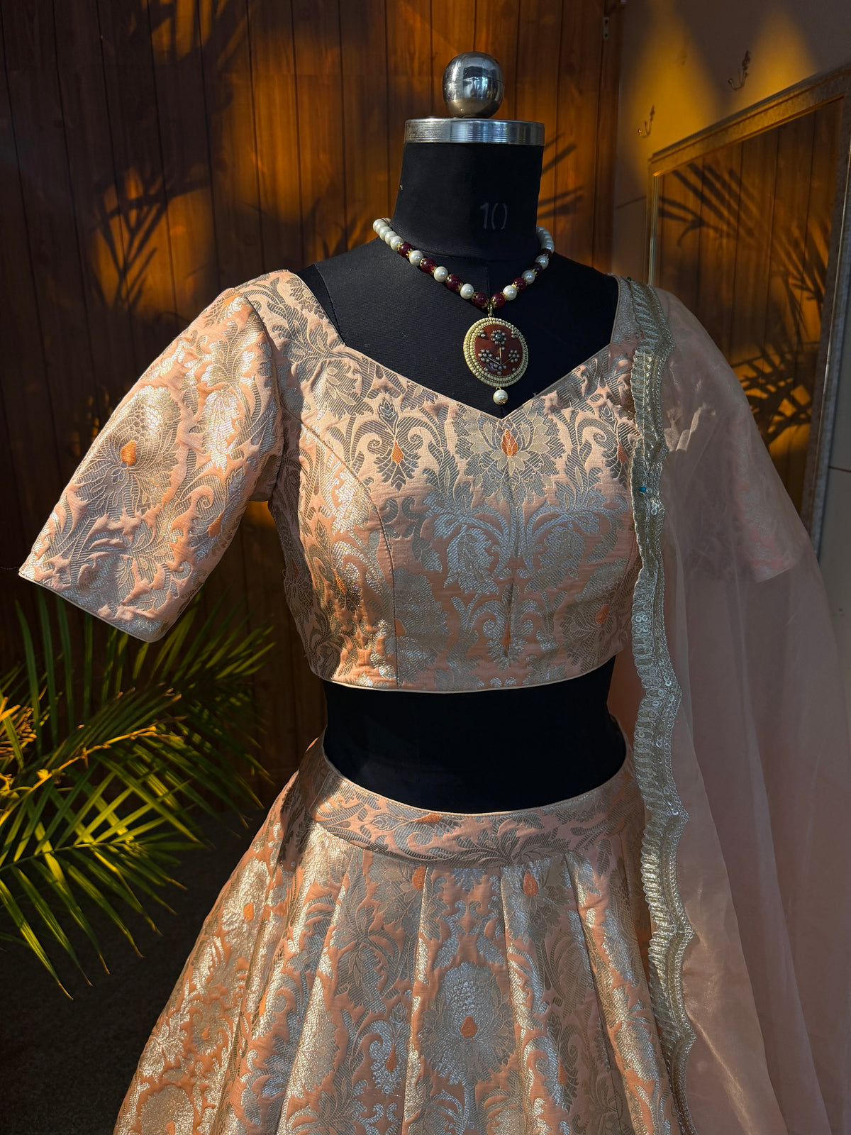 Peach and gold brocade lehenga set with sheer dupatta draped over shoulder