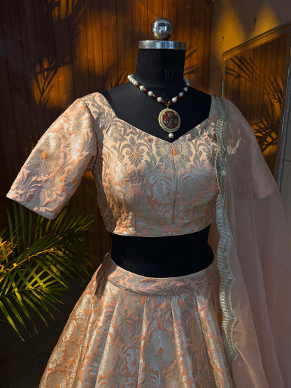 Peach and gold brocade lehenga set with sheer dupatta draped over shoulder