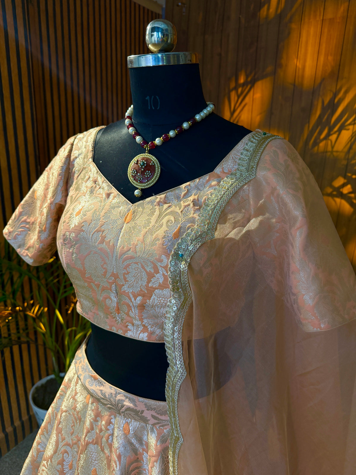 Close-up of brocade blouse neckline with scalloped gold trim and sheer dupatta drape