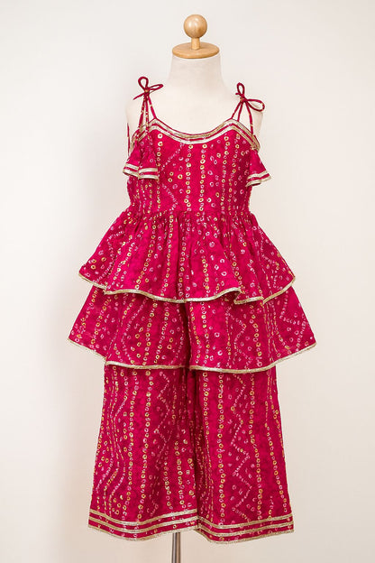 Pink tiered dress with gold patterns on a mannequin against a white background